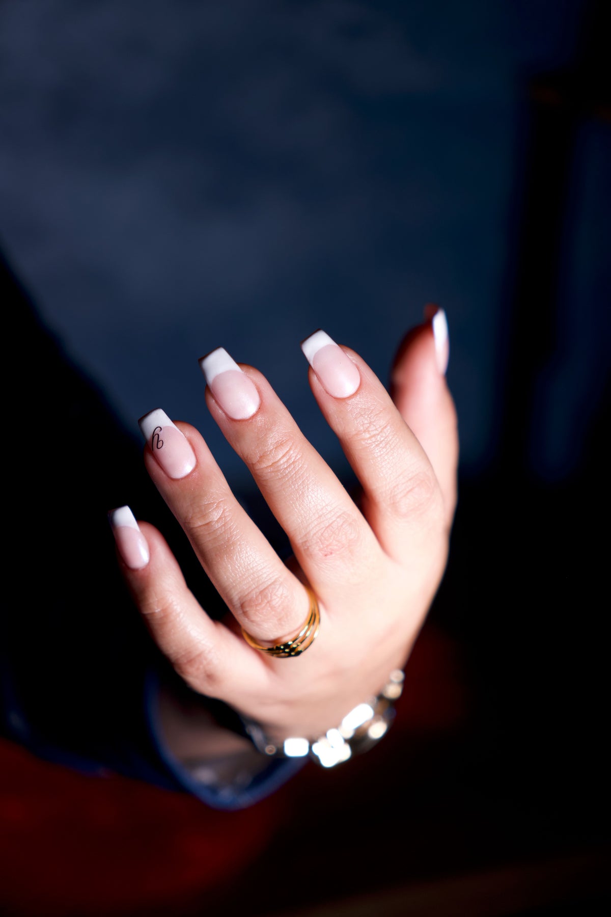 Main manucurée élégante avec bijoux sur fond sombre